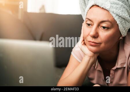 Junge Frau arbeitet am Computer zu Hause auf der Couch. Stockfoto