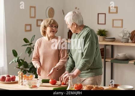 Ältere Paare diskutieren das Menü zum Abendessen, während sie zusammen kochen In der Küche Stockfoto