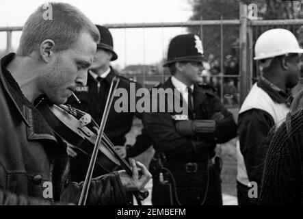 Fiddle-Spieler, die von Metropolitan Police Officers bei einem Anti-Straßen-Protest in Wanstead, East London, im Rahmen der No M11 Link Road Kampagne der direkten Aktion gegen den M11 Link Road Straßenbau im Jahr 1994 beobachtet wurden Stockfoto