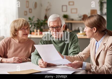 Seniorenpaar sitzt am Tisch und diskutiert mit Immobilienmakler sie machen einen Willen Stockfoto
