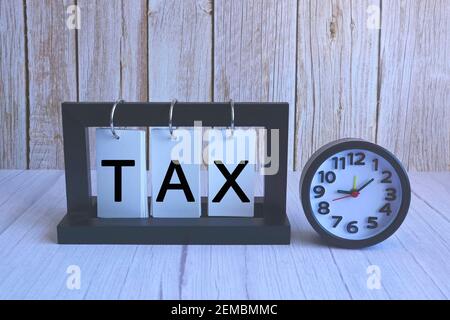 Steuertext auf Papier Standrahmen mit Wecker auf Holzhintergrund Stockfoto