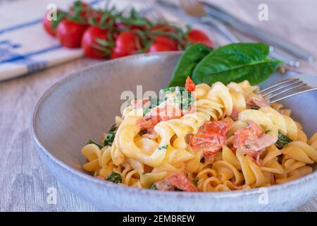 griechische Pasta mit Tomaten, Feta-Käse und Spinat auf einem Teller auf dem Küchentisch serviert Stockfoto