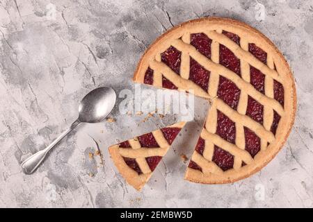 Ganze Torte namens 'Linzer Torte', ein traditionelles österreichisches Shortcake-Gebäck mit Fruchtkonserven und in Scheiben geschnittenen Nüssen mit Gitterdesign und Scheibe Stockfoto