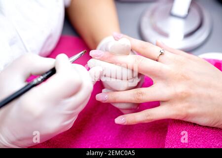Anwendung von Gel-Basis auf der Oberfläche der Nagelplatte, Maniküre für Frauen, Nagelstudio Stockfoto