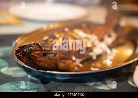 Köstlicher geräucherter Fisch auf einem Teller. Nahaufnahme, selektiver Fokus, verschwommener Hintergrund. Abendessen im Restaurant Stockfoto