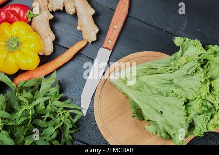 Karotte, Pfeffer, Chili, Ingwer, Salat mit Messer auf dunklem Grund Stockfoto