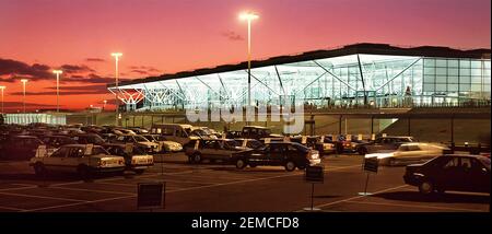 1991 Panorama-Archiv-Abendansicht kurz nach der Eröffnung in London Stanstead International Passenger Airport Terminal Gebäude mit 90s Glasfront Fassade in der Abenddämmerung mit rotem Sonnenuntergang Himmel und mehrere gesehen Ein anliegender Autovermieter ist eine historische Reise aus dem Jahr 1990s Bild in Essex England Stockfoto