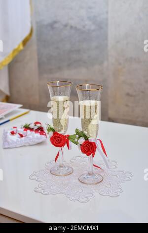 Hochzeit Champagner Gläser sind mit Rosenblumen auf dem Tisch dekoriert. Hochzeitszeremonie. Vertikales Foto. Stockfoto