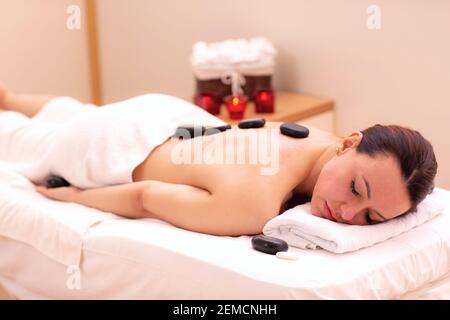 Frau mit einer Massage mit schwarzem Basaltstein, vulkanischen Energiestein, Wellness-Konzept Stockfoto