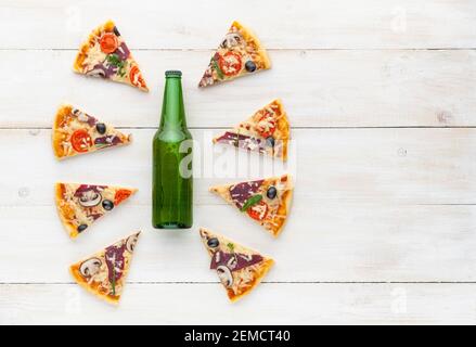 Frische Pizza im rustikalen italienischen Stil mit ruckigen Oliven Die Pilze und drei Arten des Käses auf dem hellen hölzernen Hintergrund mit einer Flasche kaltes Bier Stockfoto