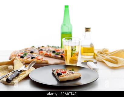 Frische Pizza im rustikalen italienischen Stil mit ruckigen Oliven Die Pilze und drei Arten des Käses auf dem hellen hölzernen Hintergrund mit einer Flasche kaltes Bier Stockfoto