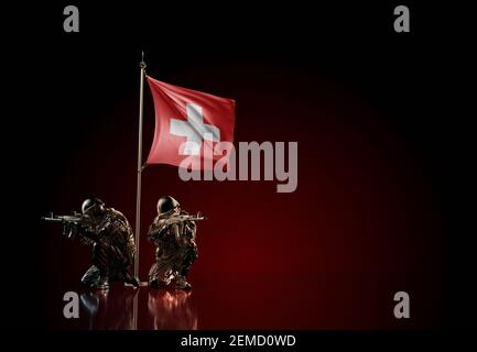 Konzept des militärischen Konflikts mit Soldatenstatuen und wehender Nationalflagge der Schweiz. Illustration der Coup-Idee. Stockfoto