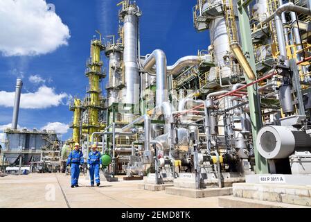 Chemische Industrie Anlage - Arbeiter in Arbeitskleidung in einer Raffinerie mit Rohren und Maschinen