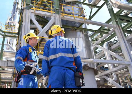 Gruppe von Industriearbeitern in einer Raffinerie - Öl verarbeitende Ausrüstung und Maschinen Stockfoto