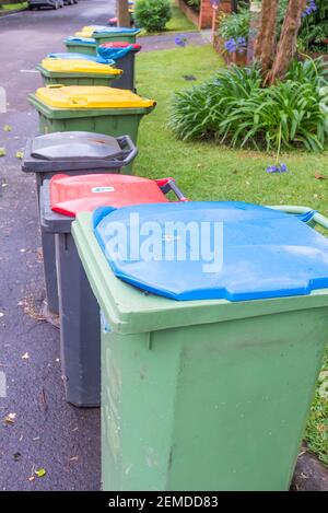 Rote (Deponie), blaue (Papier) und gelbe (comingled) lidded Abfall oder Müll oder Mülltonnen vor einem Haus in Sydney am Abholtag aufgereiht Stockfoto