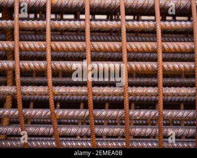 Bügeleisen auf der Baustelle. Rosty Iron Bundle für die Herstellung von Bewehrungsbeton. Rebar für Verstärkung Loch im Boden. Textur Hintergrund Netz Metall Stockfoto