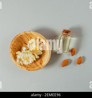 Mandelöl, natürliches Produkt für die Hautpflege Routine. Öl für die Haut befeuchten. Kleine Flasche und Mandel auf grauem Hintergrund Stockfoto