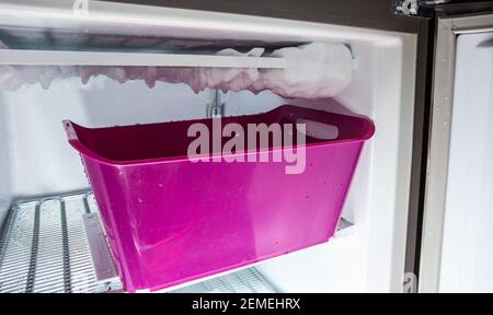 Abtauvorgang von Eis in einem heimischen Gefrierschrank. Sammeln von Wasser in einem Kunststoffbecken. Stockfoto