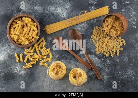 Verschiedene Arten von ungekochten Nudeln mit Holzlöffeln Stockfoto