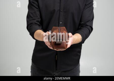 Herren braune Leder persönliche Kosmetiktasche oder Tasche für Toilettenartikel-Zubehör in einem Herrenhände in schwarzem Hemd. Stil, Retro, Mode, Vintage und Eleganz Stockfoto