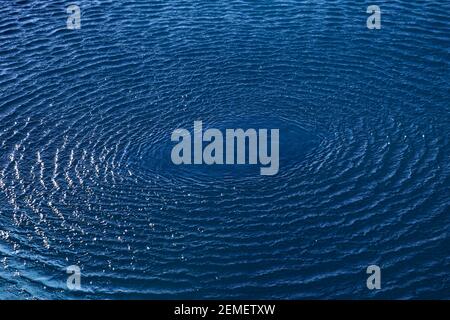 Splash: Konzentrische Kreiswellen auf blauem Süßwasser; Farbfoto. Stockfoto