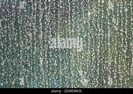 Regenwassertropfen auf Fensterglas in Kalk verwandelt; Farbfoto. Stockfoto