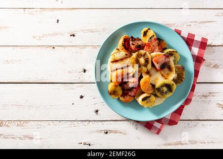 Gegrilltes Obst auf blauem Teller und weißer Holztisch Stockfoto