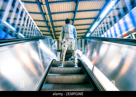 Mann, der auf der Rolltreppe des Laufbands steht, mit sanften Bewegungsunschärfen - Urban Leben Reise Konzept mit Street Fashion Kerl an U-Bahn-Station Stockfoto