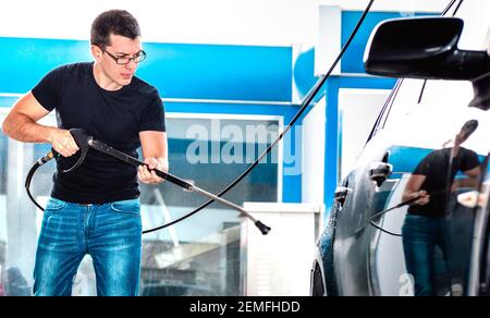 Professionelle Autowäsche Mitarbeiter Wasch Auto an der Waschstation - Arbeiten Service-Konzept mit Kerl beschäftigt mit Reinigung Auto zu öffnen Air-Geschäft Stockfoto