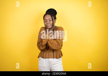 afroamerikanische Frau trägt legere Kleidung umarmt sich glücklich und positiv, lächelnd zuversichtlich Stockfoto