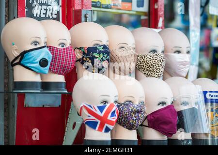 London, UK - 5 Februar, 2021 - Tuch Gesichtsmasken mit verschiedenen Mustern auf Schaufensterpuppe Köpfe zum Verkauf auf Wood Green High Street angezeigt Stockfoto