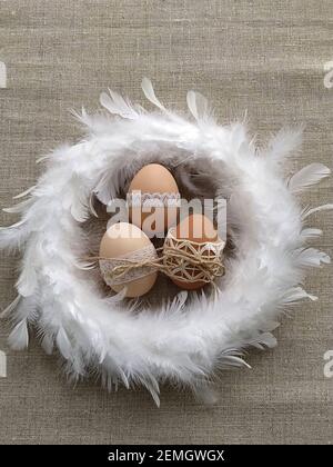 Ostern Komposition verziert mit Spitze Ostereier in weißen Feder Kranz auf Leinenhintergrund Stockfoto