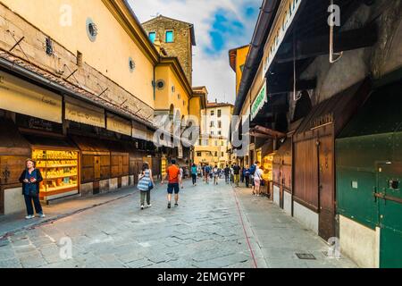 Italienische Juweliergeschäfte auf der Brücke Ponte Vecchio in Florenz. Die Menschen überqueren die Brücke und machen einen Spaziergang, um die Geschäfte unter dem... Stockfoto