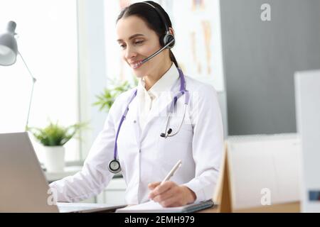 Ärztin mit Headset, die in den Laptop-Bildschirm schaut Stockfoto