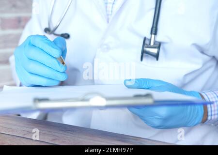 Arzt Hand in Latexhandschuhe schreiben Rezept auf Schreibtisch, Nahaufnahme. Stockfoto