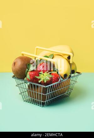 Warenkorb mit frischen Früchten auf grünem und gelbem Hintergrund Stockfoto