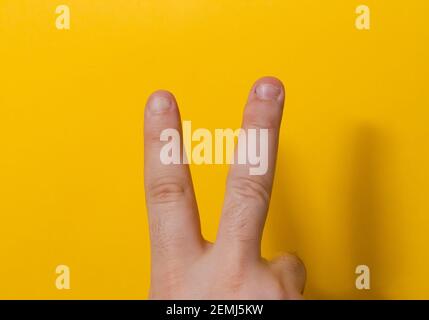 Nahaufnahme Male zwei Finger mit gebissen, gefwaned, gekaut oder hässlichen Nägeln, ein bisschen schlechten Nagel und isoliert auf einem gelben Hintergrund Stockfoto