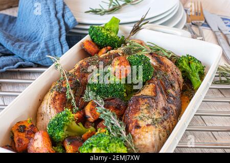 Gebratenes Schweinefilet mit mediterranem Gemüse wie Süßkartoffeln Und Brokkoliblüten in einer Kasserolle auf einem Holztisch serviert Stockfoto