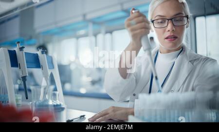 Medical Research Laboratory: Portrait einer schönen Wissenschaftlerin in Goggles mit Mikropipette für die Testanalyse. Advanced Scientific Lab für Stockfoto