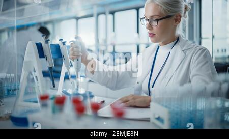 Medical Research Laboratory: Portrait einer schönen Wissenschaftlerin in Goggles mit Mikropipette für die Testanalyse. Advanced Scientific Lab für Stockfoto