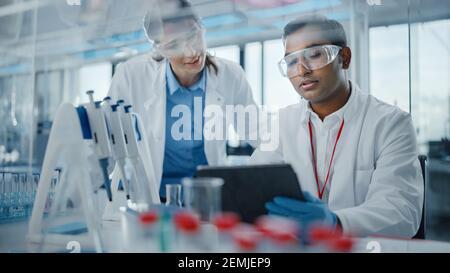 Modernes Medizinisches Forschungslabor: Zwei Wissenschaftler Arbeiten Zusammen, Analysieren Proben Und Diskutieren Über Innovative Technologie. Advanced Scientific Lab für Stockfoto