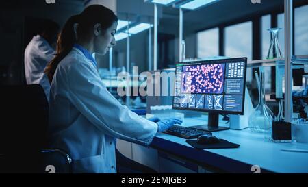 Modernes medizinisches Forschungslabor: Portrait einer Wissenschaftlerin, die am Computer arbeitet, Biochemikalien analysiert, spricht. Advanced Scientific Lab für Stockfoto