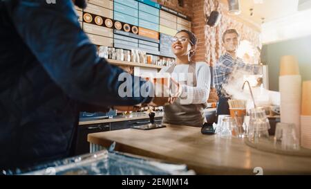 Black African American Food Delivery Courier holt zwei Kaffee und Gebäck zum Mitnehmen aus einem Cafe Restaurant. Glückliches, vielfältiges Personal gibt den Auftrag Stockfoto