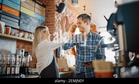 Zwei verschiedene Unternehmer haben ein Team Meeting in ihrem stilvollen Coffee Shop. Barista und Cafe-Besitzer besprechen Arbeitsplan und Menü auf dem Tablet-Computer Stockfoto