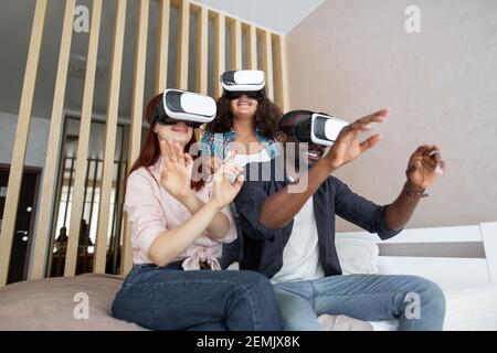 Unglaublich. Überrascht erstaunt nette Familie winkende Hände beim Versuch VR-Brille und Ruhe auf dem schlechten. Multirassische Familie jubelt zu Hause. Technolo Stockfoto