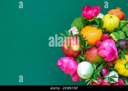 Anordnung von verschiedenen Gemüse und Frühlingsblumen auf einem satten grünen Hintergrund. Das Konzept eines gesunden Lebensstils Stockfoto