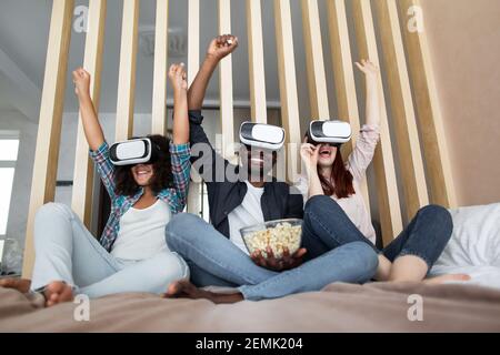 Ich fühle mich aufgeregt. Erstaunt bärtigen schwarzen Mann ruht mit seiner europäischen Frau und Tochter mit Virtual-Reality-Geräte. Leute essen Popcorn und Wachin Stockfoto