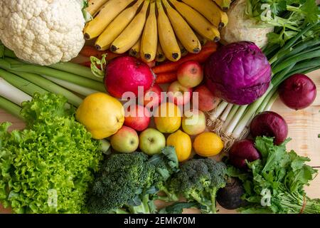 Füllen Sie Ihren Kühlschrank mit gesundem Gemüse und Obst. Viele Gemüse und Früchte sitzen auf dem Tisch. Stockfoto