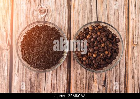 Teeblätter für Infuser und gerösteten Kaffee Körner verpackt in Tassen auf einem Holztisch Stockfoto