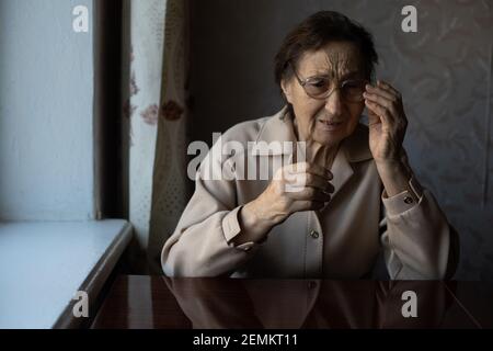 Sehr alte Frau zieht eine Brille an Stockfoto